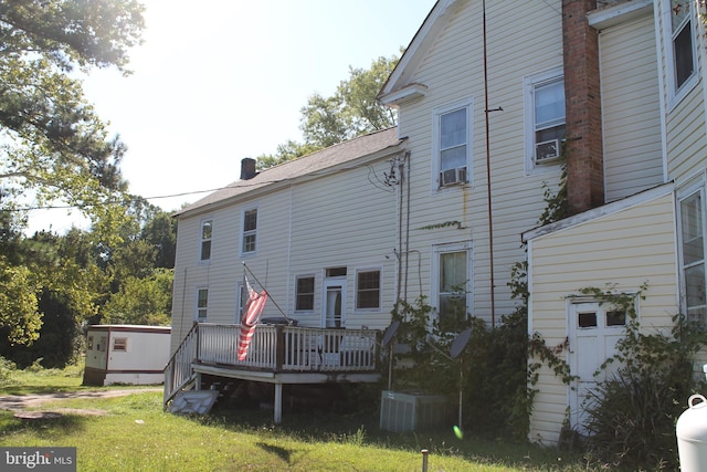 rear view of property with a deck, a lawn, and cooling unit