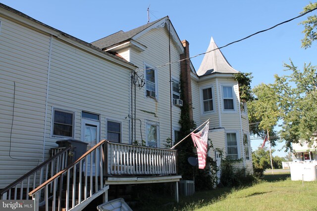 back of house with cooling unit, a deck, and a lawn