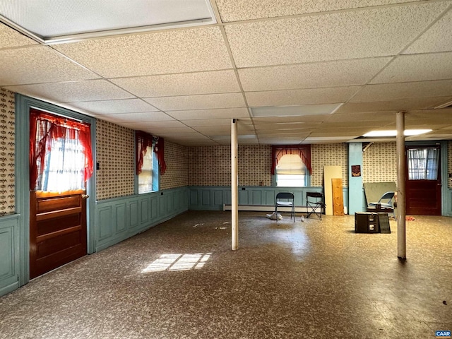 basement featuring wainscoting and a drop ceiling