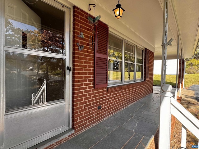 view of exterior entry featuring a porch and brick siding