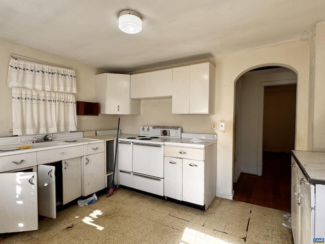 kitchen with light countertops, white cabinetry, electric range, light floors, and arched walkways