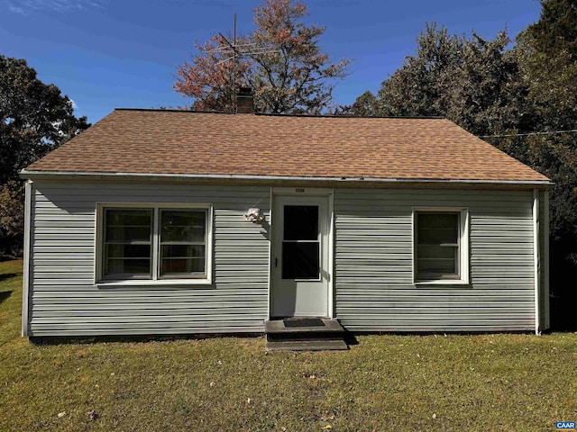 bungalow-style house with a front lawn, a shingled roof, and a chimney