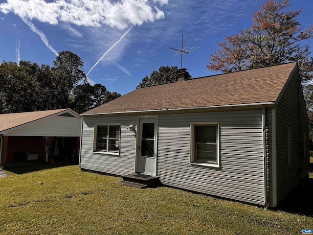 view of front of home with entry steps, a chimney, a shingled roof, and a front yard