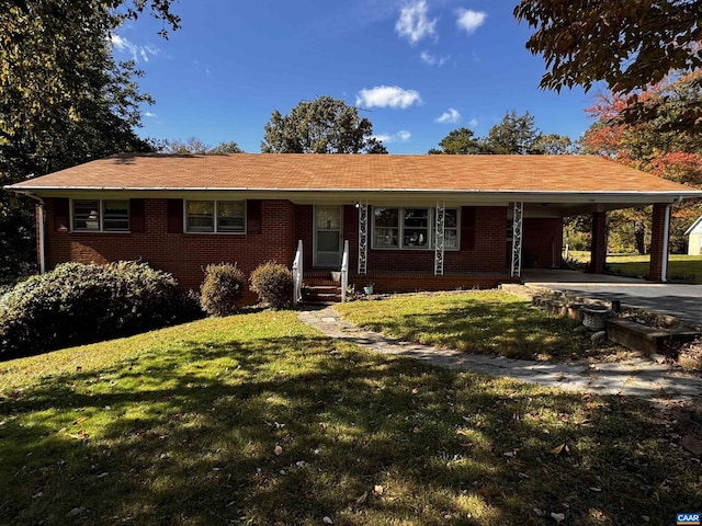 single story home with a front yard, brick siding, an attached carport, and driveway