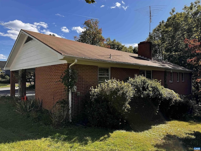 view of side of home with brick siding, a yard, and a chimney