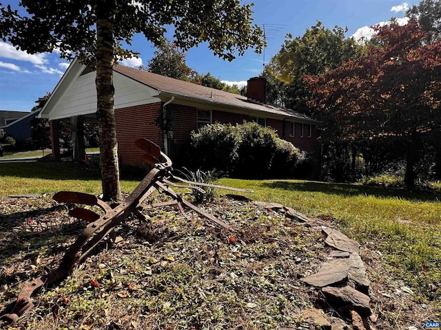 view of property exterior featuring brick siding, a yard, and a chimney