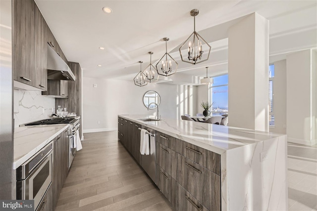 kitchen featuring a spacious island, backsplash, decorative light fixtures, light hardwood / wood-style flooring, and exhaust hood