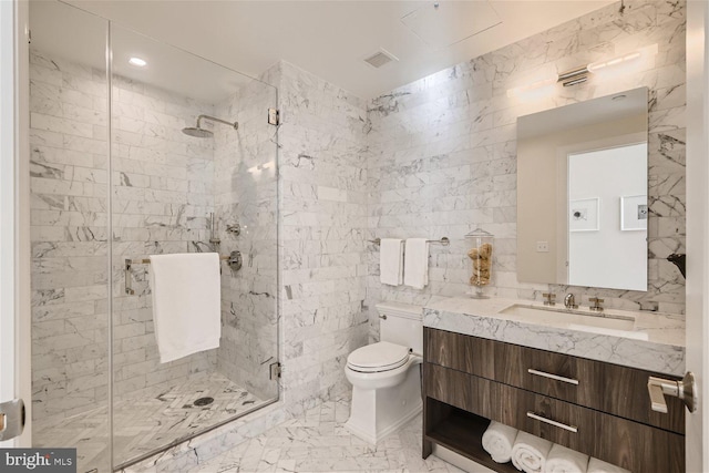 bathroom with vanity, a shower with shower door, toilet, and tile walls