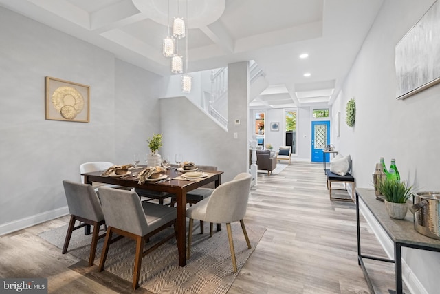 dining space featuring beam ceiling, coffered ceiling, and light hardwood / wood-style flooring