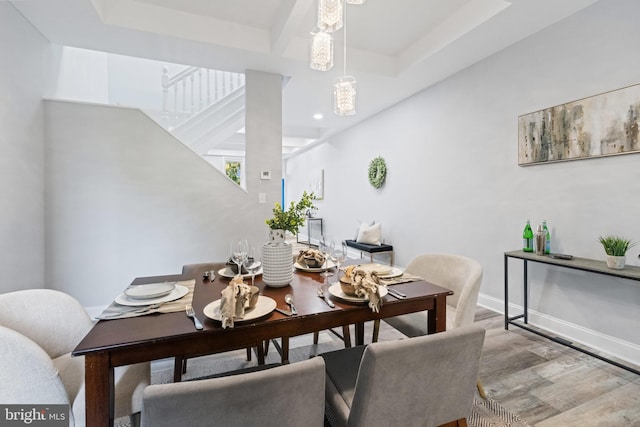 dining space with hardwood / wood-style flooring and a raised ceiling