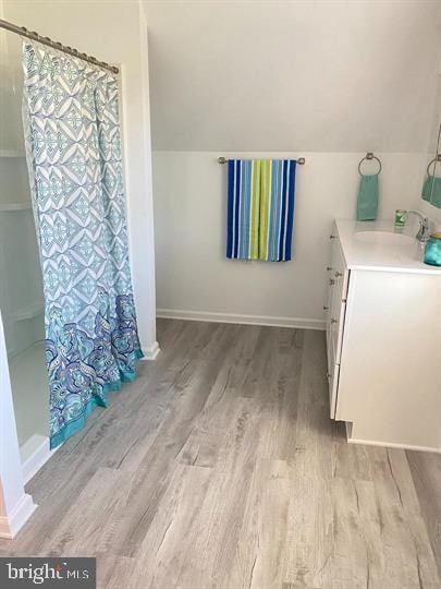 bathroom featuring vanity, wood-type flooring, lofted ceiling, and curtained shower