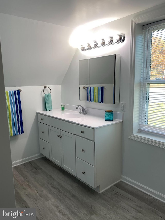 bathroom featuring vanity, wood-type flooring, and vaulted ceiling