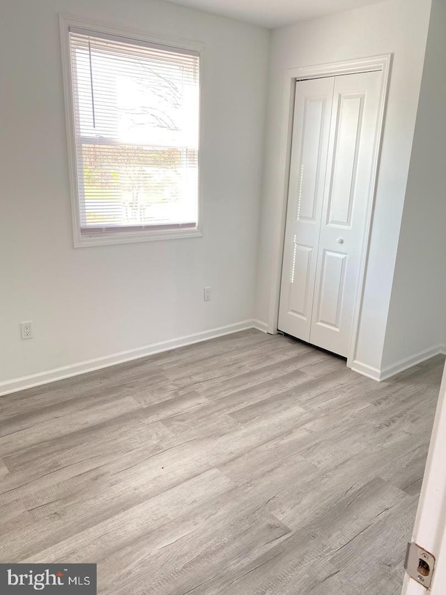 unfurnished bedroom featuring light hardwood / wood-style floors and a closet