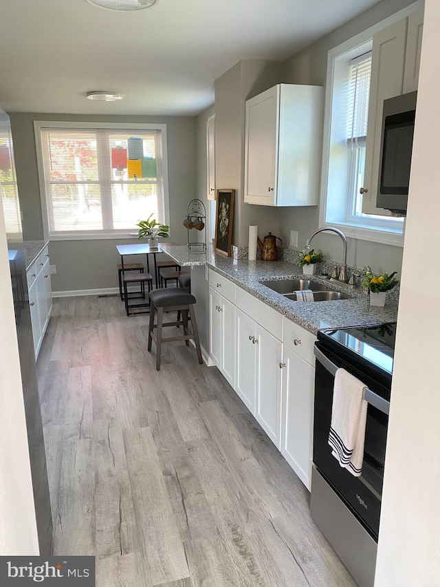 kitchen featuring sink, white cabinetry, light stone counters, and stainless steel appliances