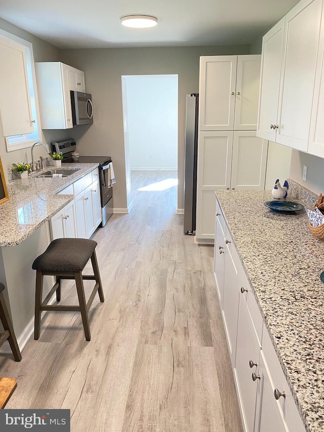 kitchen featuring white cabinets, stainless steel appliances, and light wood-type flooring