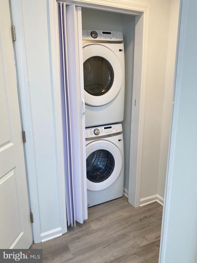 clothes washing area with stacked washer / dryer and light hardwood / wood-style flooring