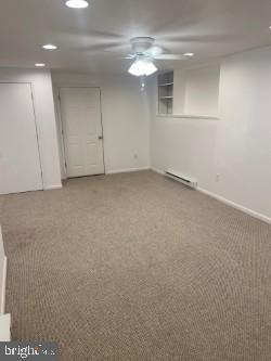 unfurnished room with a baseboard radiator, carpet, and ceiling fan