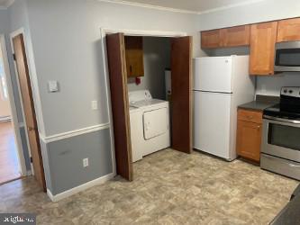 kitchen featuring appliances with stainless steel finishes, ornamental molding, and washer / dryer