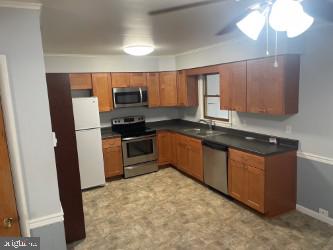 kitchen with ornamental molding, sink, appliances with stainless steel finishes, and ceiling fan