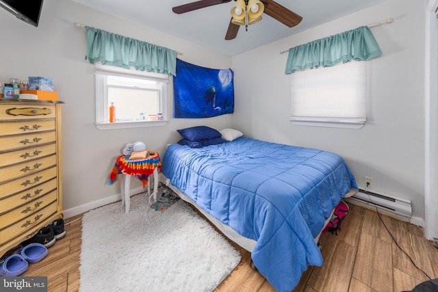 bedroom featuring a baseboard heating unit, hardwood / wood-style flooring, and ceiling fan