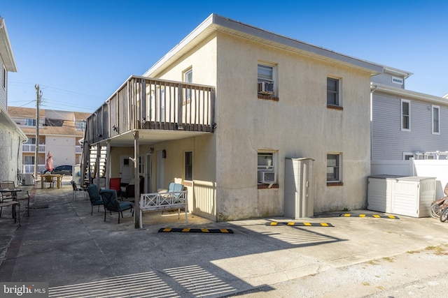 back of house featuring a storage unit, cooling unit, and a patio