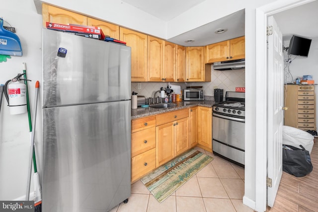 kitchen featuring tasteful backsplash, sink, light tile patterned flooring, stainless steel appliances, and dark stone counters