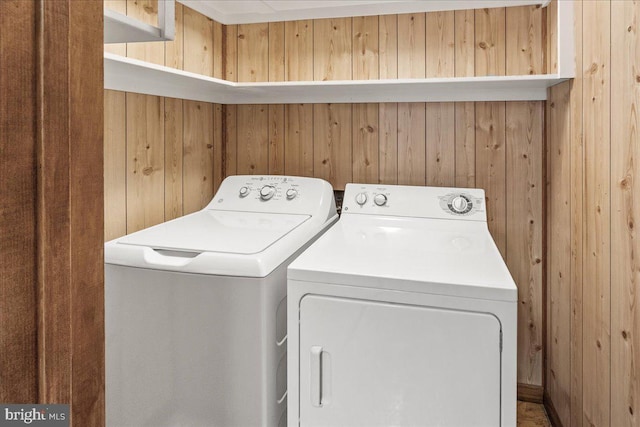 washroom featuring wooden walls and washer and dryer