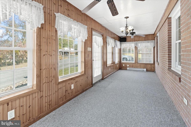 unfurnished sunroom featuring ceiling fan with notable chandelier, a baseboard radiator, and a wealth of natural light