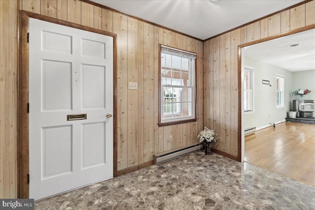 foyer with baseboard heating, wood-type flooring, plenty of natural light, and wood walls