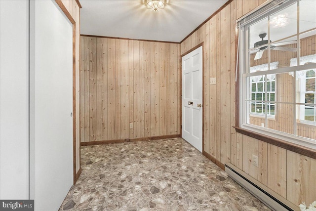 interior space with ornamental molding, wood walls, baseboard heating, and ceiling fan