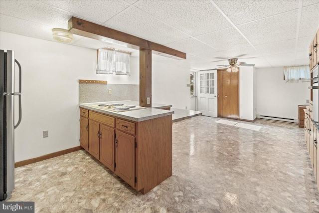 kitchen with a baseboard heating unit, kitchen peninsula, white stovetop, a paneled ceiling, and stainless steel refrigerator