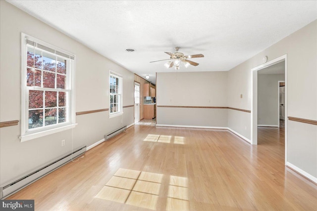 empty room featuring a baseboard heating unit, a textured ceiling, and light wood-type flooring