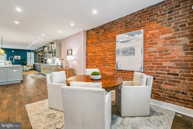 dining space featuring brick wall and hardwood / wood-style flooring