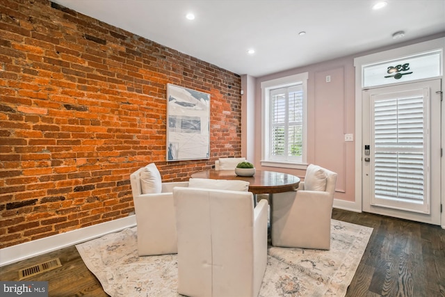 dining space with brick wall and dark hardwood / wood-style floors