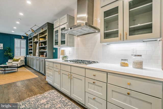 kitchen featuring dark wood-type flooring, wall chimney exhaust hood, gray cabinets, and stainless steel gas stovetop