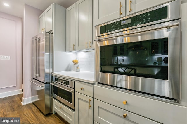 kitchen with dark wood-type flooring, white cabinetry, stainless steel appliances, and tasteful backsplash