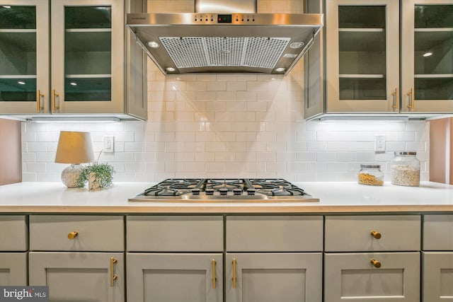 kitchen featuring wall chimney range hood, tasteful backsplash, gray cabinets, and stainless steel gas cooktop