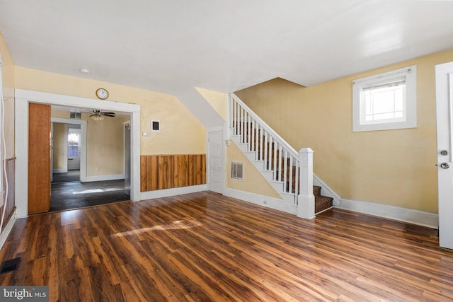 interior space with wood walls, dark wood-type flooring, and ceiling fan