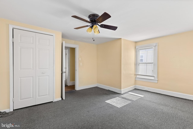 unfurnished bedroom featuring a closet, ceiling fan, and dark colored carpet