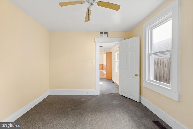 unfurnished room featuring dark colored carpet and ceiling fan