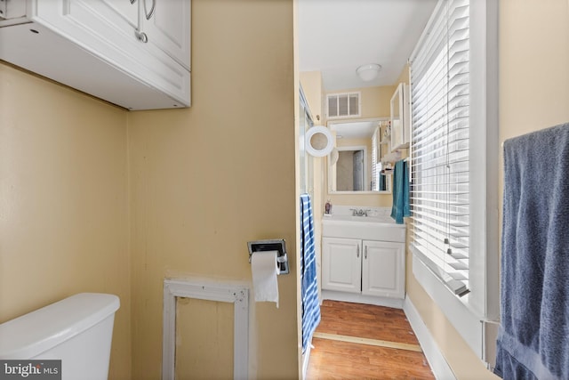 bathroom with toilet, vanity, and wood-type flooring