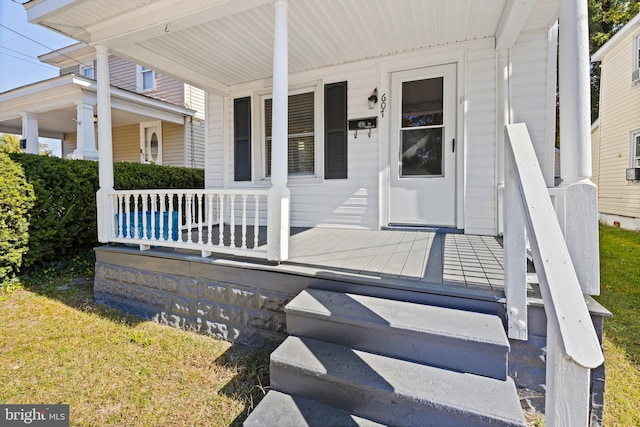 property entrance featuring covered porch and a lawn