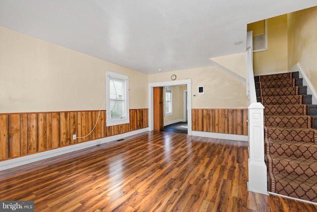 unfurnished living room featuring dark wood-type flooring and wooden walls