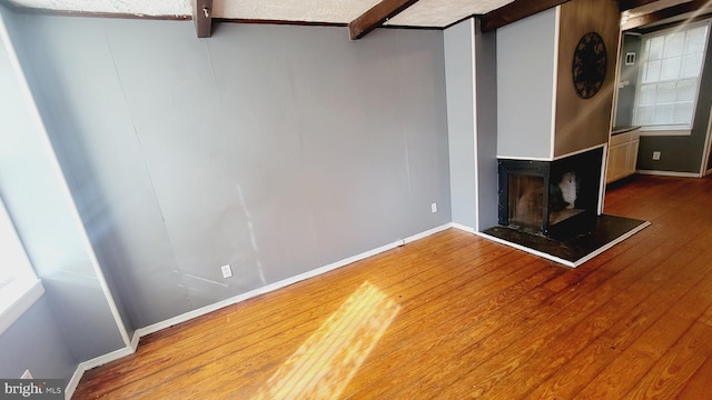 unfurnished living room featuring beamed ceiling and hardwood / wood-style flooring