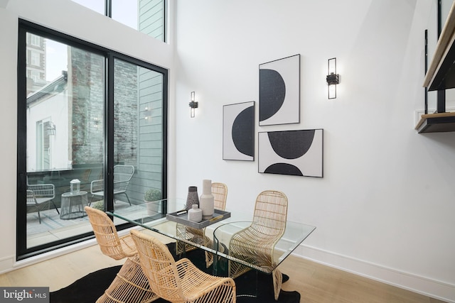 dining room featuring a towering ceiling and light wood-type flooring