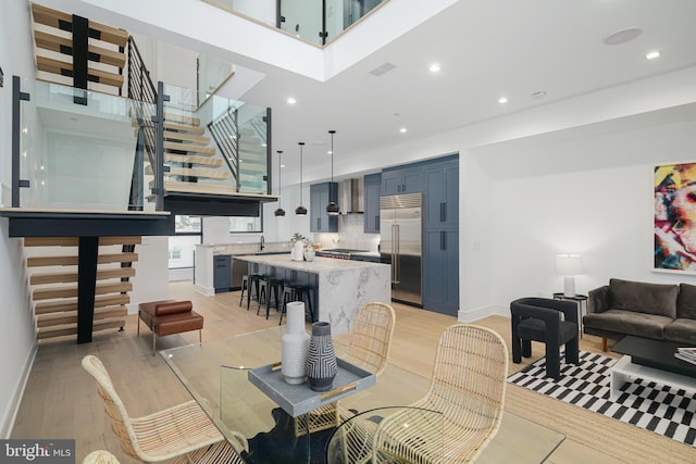 dining room with light hardwood / wood-style flooring and a towering ceiling