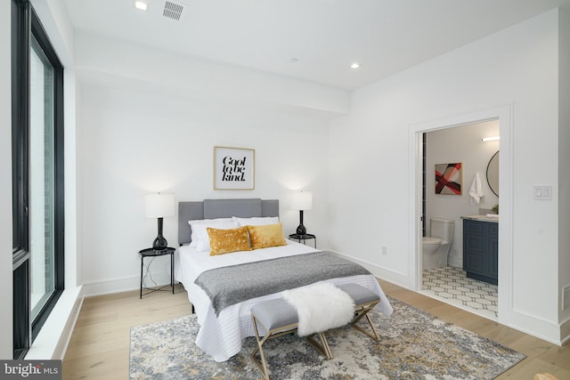 bedroom featuring ensuite bath and light wood-type flooring