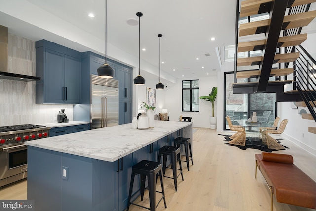 kitchen with a kitchen island, blue cabinetry, light hardwood / wood-style floors, decorative light fixtures, and high end appliances