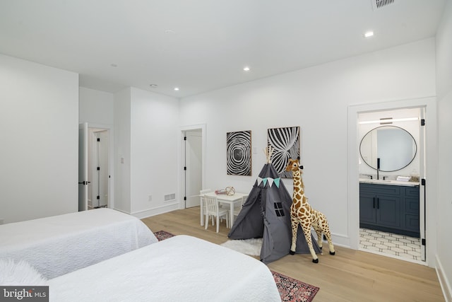 bedroom with ensuite bathroom and light hardwood / wood-style floors