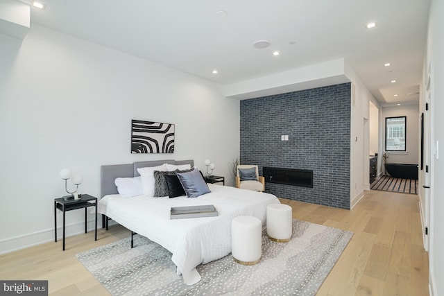 bedroom with a large fireplace and light wood-type flooring